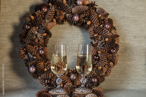 Wine glasses with champagne on the background of a Christmas wreath in a natural style. Christmas composition.