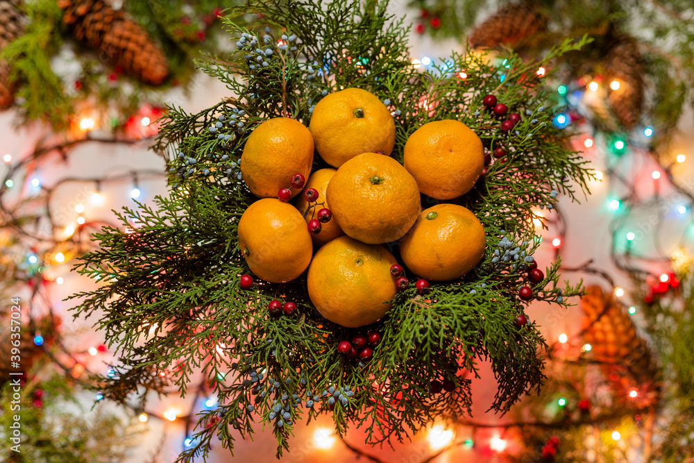 Christmas natural decoration with lots of tangerines in basket and christmas lights behind