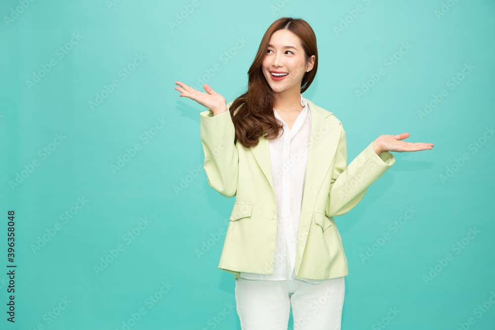 Happy Asian woman presenting or showing open hand palm with copy space for product isolated over green background Happy Asian woman presenting or showing open hand palm with copy space for product isolated over green background