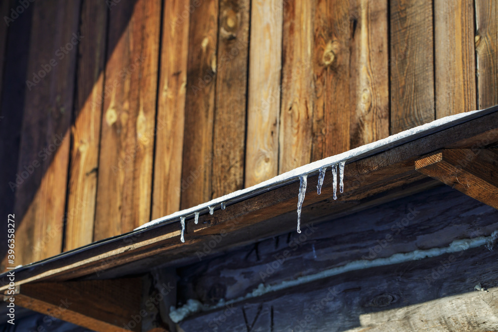 Icicles on the roof of a village house on a sunny winter day. Icicles on the roof of a village house on a sunny winter day.