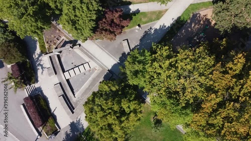 aerial birds eye view over empty modern futuristic park at a metroplolis with empty steps leading to a dry contemperary stylish fountain water sprinklers in the summer where its sunny lush green 3-3 photo