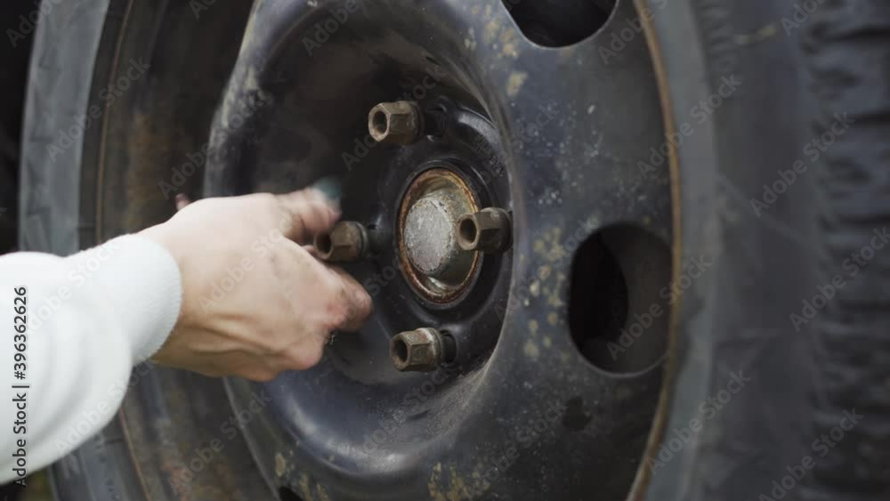A girl with a manicure changes a car wheel, jack, wrench, grease. close-up. A girl with a manicure changes a car wheel, jack, wrench, grease. close-up.