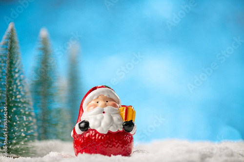 Toy Santa Claus and Christmas trees on abstract light blue background with copy space © Ivan Karpov