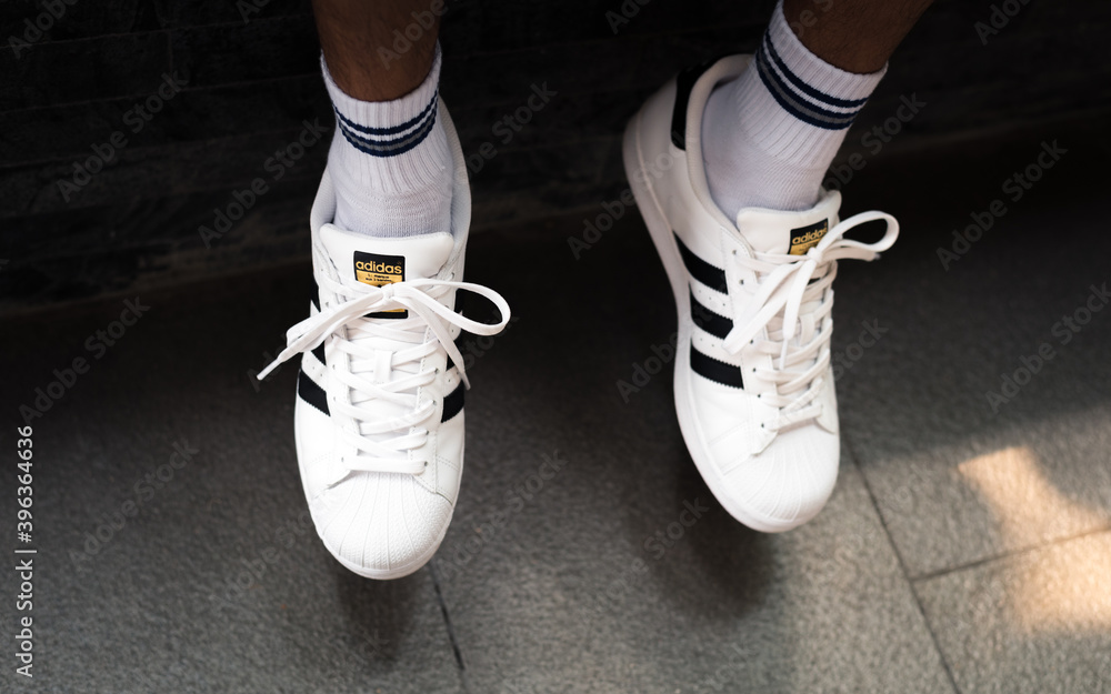 Closeup of white Adidas Superstar sneakers on man's feet on May 20, 2019 in  Bangkok, Thailand. Photos | Adobe Stock