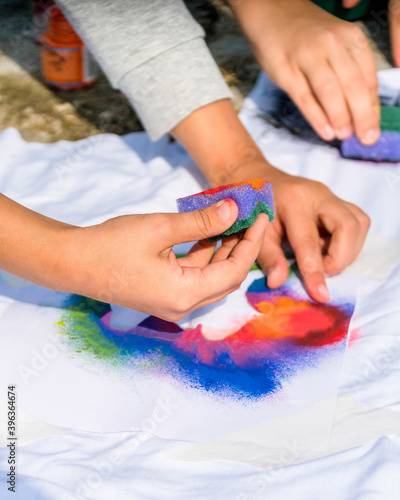 Creating your own t-shirt workshop outside. Hand applying paint