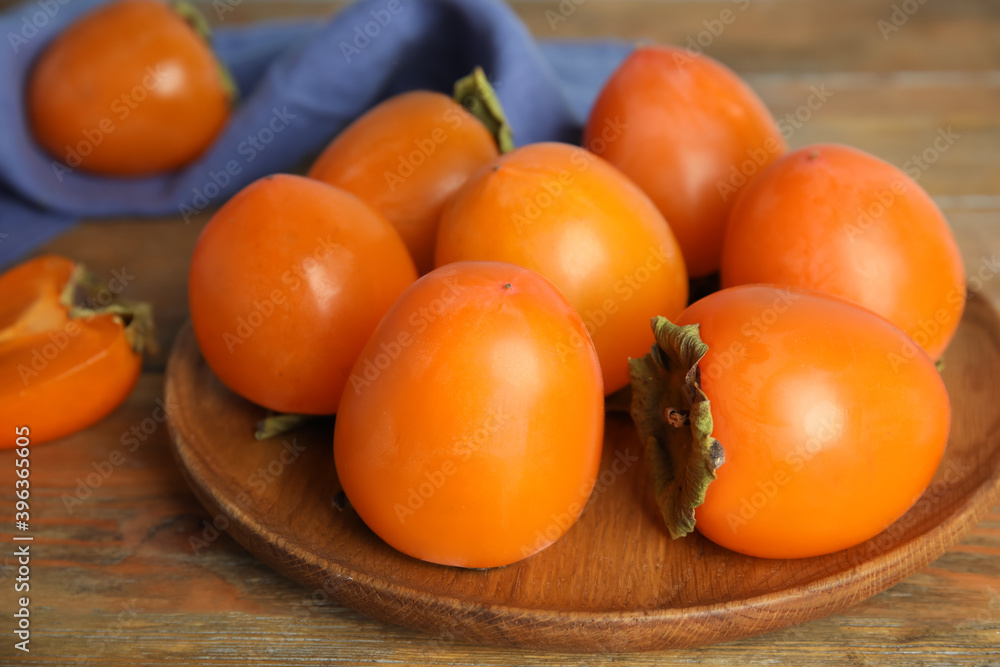 Tasty ripe persimmons on wooden table, closeup