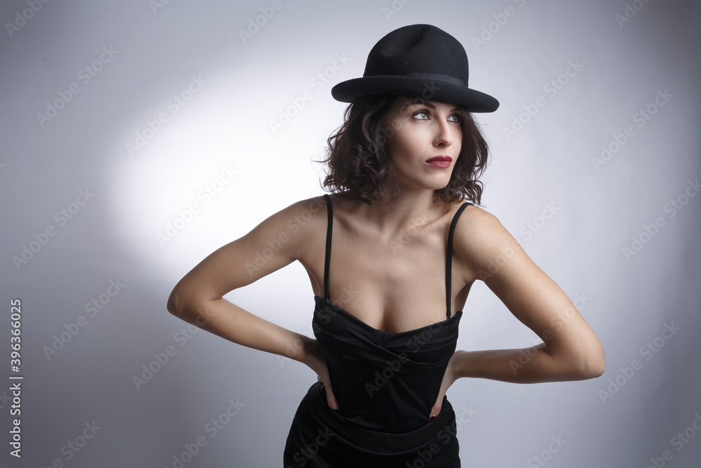 bella ragazza mora con cappello e canottiera nera posa isolata su sfondo nero bella ragazza mora con cappello e canottiera nera posa isolata su sfondo nero
