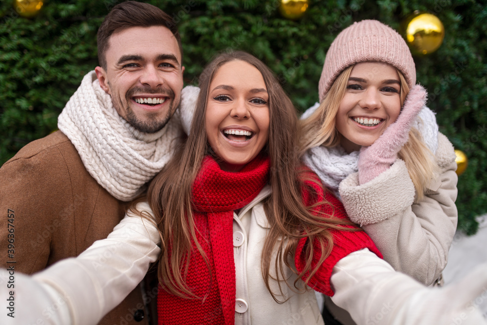 Happy woman taking Christmas selfie with friends Happy woman taking Christmas selfie with friends