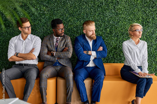 Quadro su tela group of male colleagues sit looking at new employee, keep away from female work