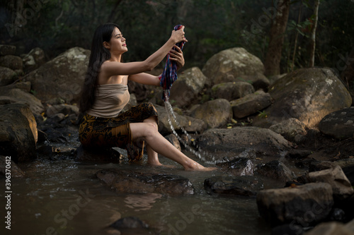 Portrait Asian young woman washing clothes at the stream.Beautiful Village women sitting and washing the clothes at the river.Countryside life style concept.