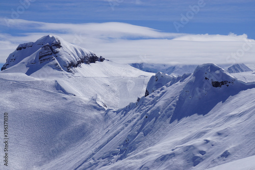 ski slopes in the French Alps with snow covered mountains on a sunny day mixed with clouds