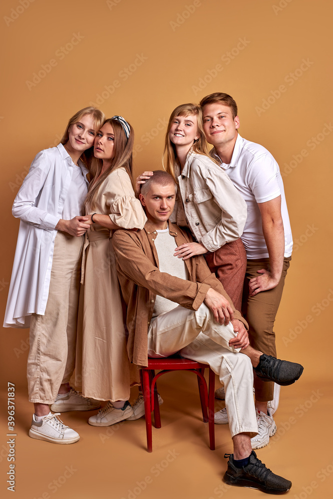 stylish friends of bossy photogenic man on chair, stand together posing, young generation portrait