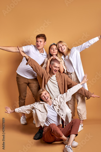 cheerful young people spread arms, ready to fly like a plane, have fun together posing and laughing