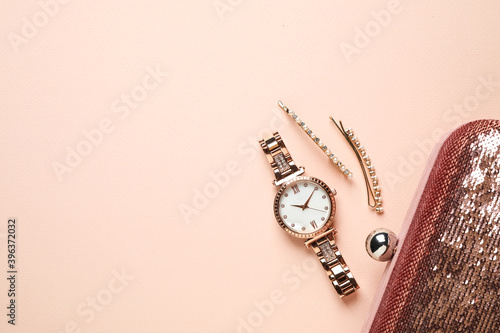 Luxury wrist watch, hairpins and clutch on pink background, flat lay. Space for text