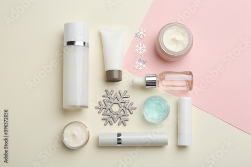 Flat lay composition with cosmetic products on pink and beige background. Winter care