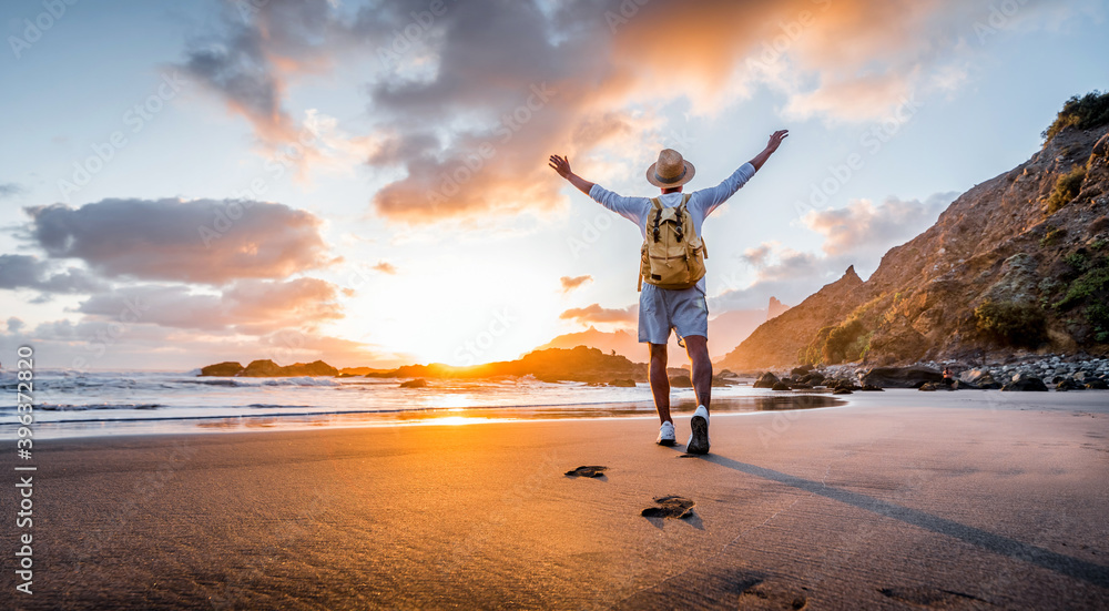 Plakat Happy and successful man raising arms up on the beach at sunset - Mental health, success, happiness and travel.