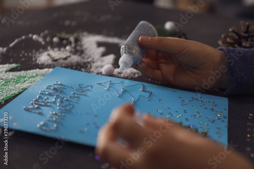 Little child making Christmas card at table, closeup