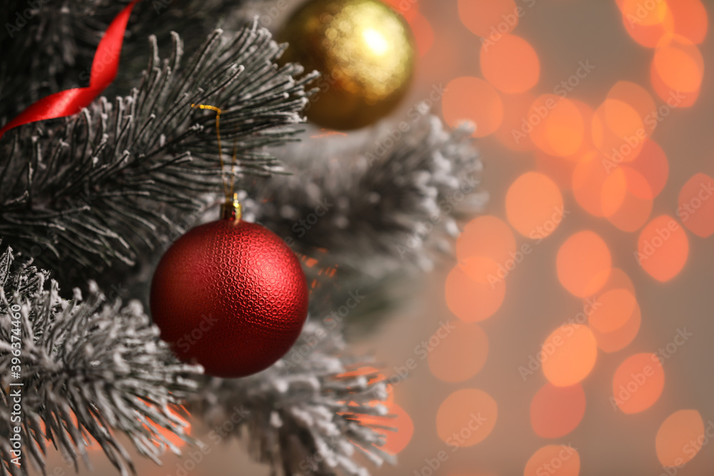 Red holiday bauble hanging on Christmas tree against blurred festive lights, closeup. Space for text Red holiday bauble hanging on Christmas tree against blurred festive lights, closeup. Space for text