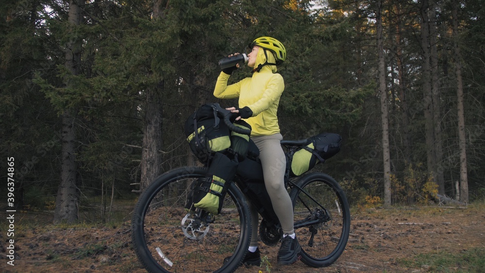 The woman travel on mixed terrain cycle touring with bike bikepacking. The traveler journey with bicycle bags. Magic forest park. The woman travel on mixed terrain cycle touring with bike bikepacking. The traveler journey with bicycle bags. Magic forest park.
