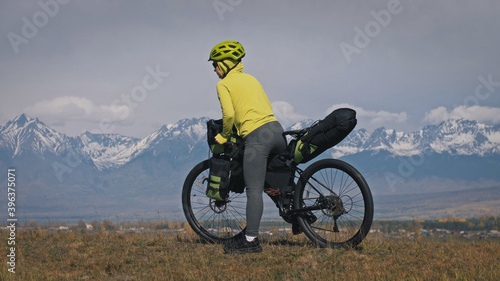 Fototapeta Naklejka Na Ścianę i Meble -  The woman travel on mixed terrain cycle touring with bikepacking. The traveler journey with bicycle bags. Sport tourism bikepacking.