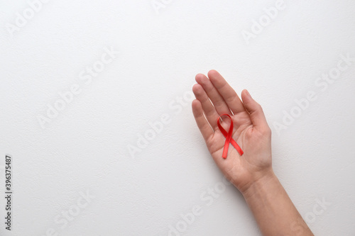 Woman holding red awareness ribbon on white background, top view with space for text. World AIDS disease day