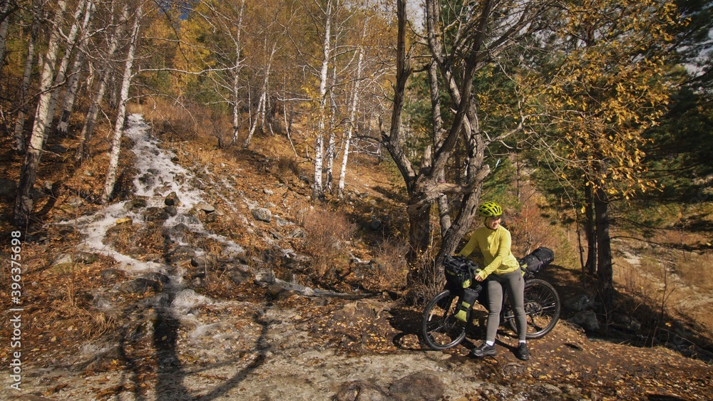Obraz premium The woman travel on mixed terrain cycle touring with bikepacking. The traveler journey with bicycle bags. Sport tourism bikepacking.