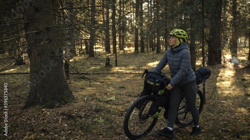 The woman travel on mixed terrain cycle touring with bike bikepacking. The traveler journey with bicycle bags. Magic forest park.