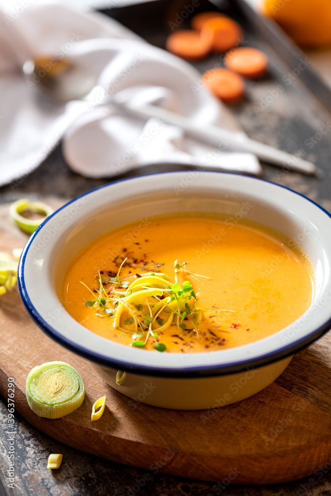 Tasty carrot creamy soup with herbs and spices in a bowl close-up. Soft focus. Autumn or winter food. Pureed vegetable soup. Tasty carrot creamy soup with herbs and spices in a bowl close-up. Soft focus. Autumn or winter food. Pureed vegetable soup.