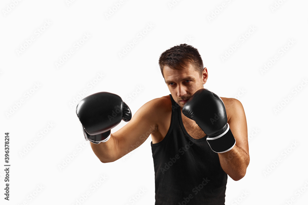 Handsome muscular man in black boxing gloves punching isolated on white background.