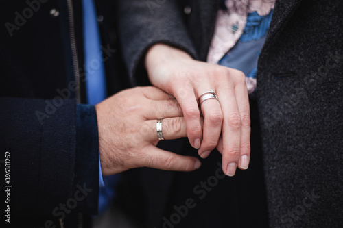 A young couple is holding hands. Wedding rings on the finger of the bride and groom close up. Wedding day. 
