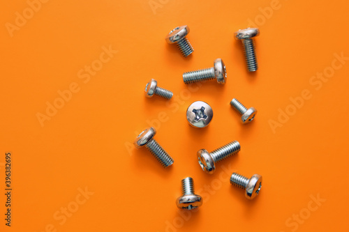 Metal drywall screws on a yellow background, top view, cross screw cap