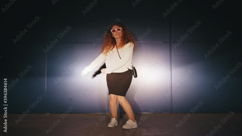 Dancing woman funny happy rhythmically waving his arms against blue textured street wall evening summer. Playful crazy female with long red hair dance emotions. Freestyle dance. Lifestyle Dancing woman funny happy rhythmically waving his arms against blue textured street wall evening summer. Playful crazy female with long red hair dance emotions. Freestyle dance. Lifestyle