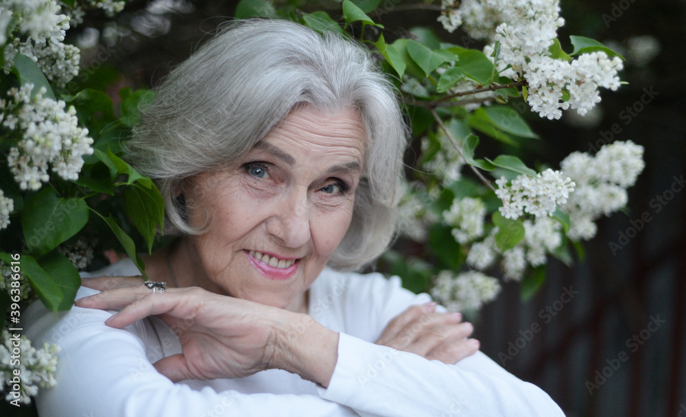 Senior beautiful woman posing with lilacs in park Senior beautiful woman posing with lilacs in park