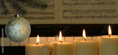 christmas decoration with four burning candles, spruce branch, piano and music paper