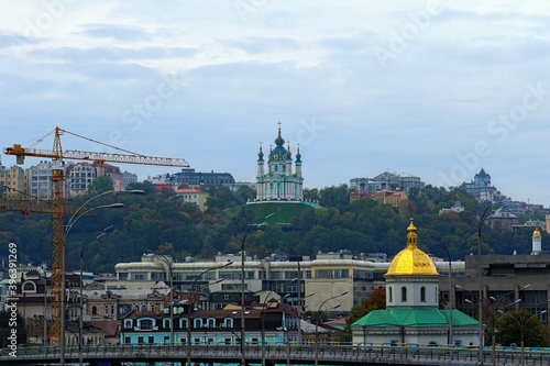 Picturesque view of St. Andrew's Church at the hill. One of the oldest district in Kyiv ? Podil. Autumn sunrise. Morning cityscape of Kyiv (Kiev) against cloudy sky, Ukraine photo