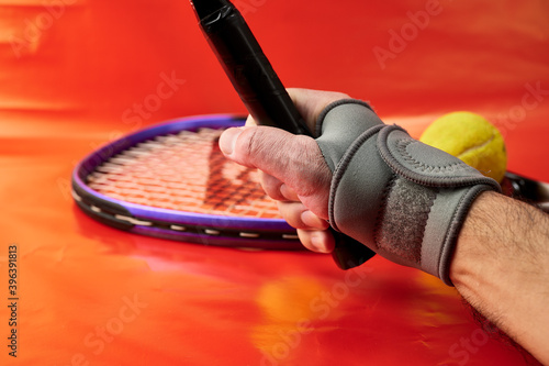 Mano de hombre con una muñequera y raqueta de tenis photo