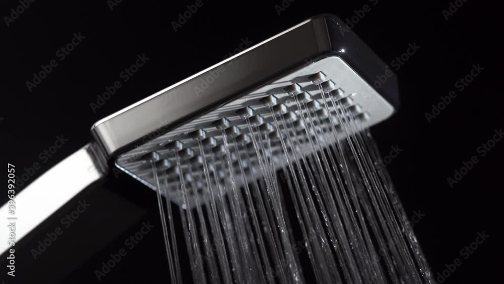 Water running from shower head in bathroom with black background. Concept home interior and design. Close up Water running from shower head in bathroom with black background. Concept home interior and design. Close up