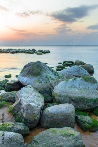 Sunset on stone coastline, rocky beach of gulf of Riga in Latvia.