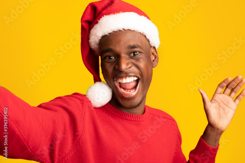 Festive Selfie. Cheerful Black Guy In Santa Hat Taking Self-Portrait, Celebrating Christmas © Prostock-studio