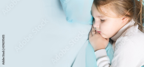 Little brunette girl sleeps sweetly in bed with blue linen. space for text. healthy baby s sleep. top view