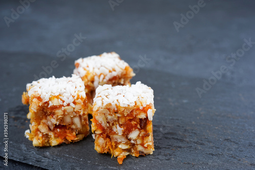 Raw candies with dried fruits on slate plate, gray concrete background. Vegan dessert, confectionery, recipe concept. Close-up, copy space