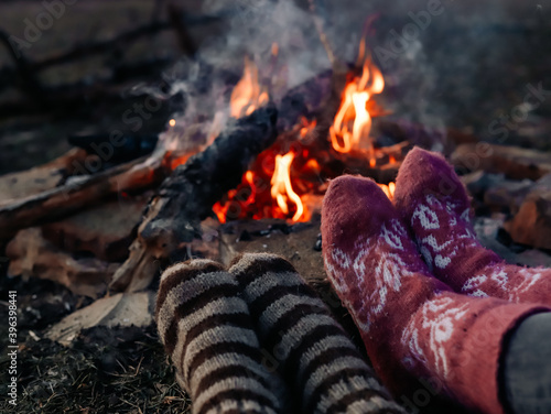 Feet in knitted socks are warming up near the bonfire. © Юлия Мачулан