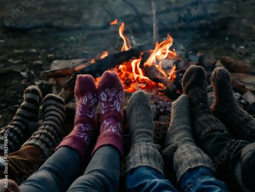 Feet in knitted socks are warming up near the bonfire.