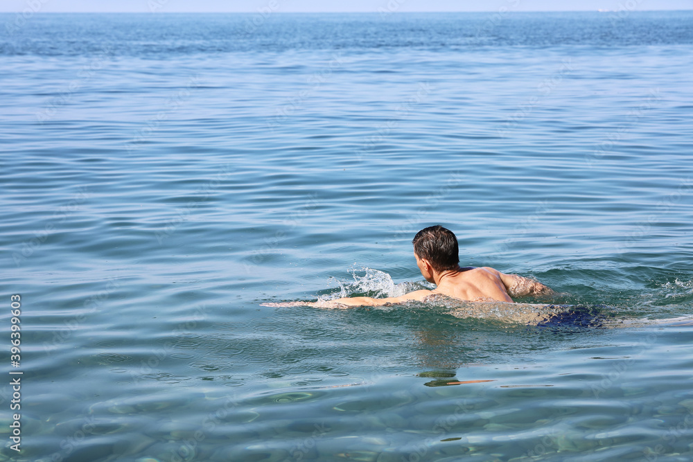 Swimmer swims on the surface of the water in the sea on sunny day, with copy space