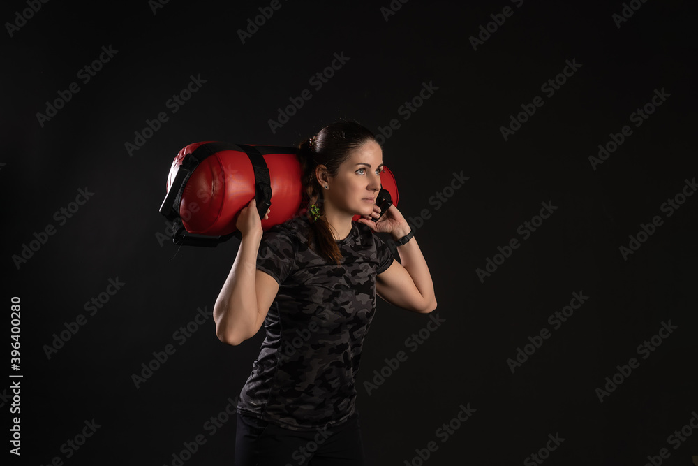 Fitness woman with Aqua Bag, on the shoulders at an angle. Engaged in sports on a black background Joyful looks at the camera Fitness woman with Aqua Bag, on the shoulders at an angle. Engaged in sports on a black background Joyful looks at the camera