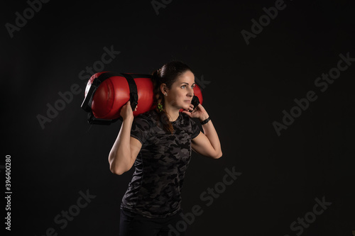 Fitness woman with Aqua Bag, on the shoulders at an angle. Engaged in sports on a black background Joyful looks at the camera