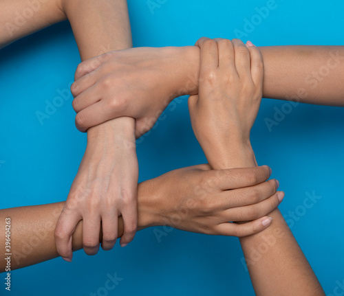Unrecognizable Women Holding Hands Symbolizing Togetherness, Blue Background, Cropped