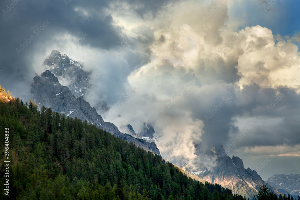 The mountain peaks of the Alps are shrouded in thick clouds. Evening light.