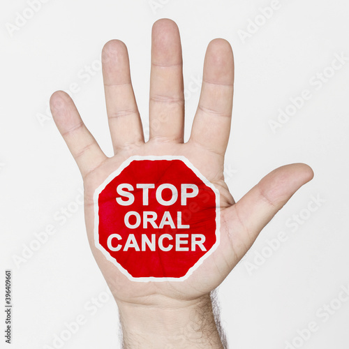 On the palm of the hand there is a stop sign with the inscription - STOP ORAL CANCER. Isolated on white background.