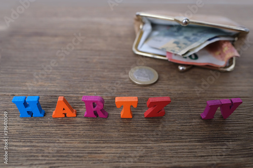 money, euro banknotes, black wallet, word in German Hartz IV made of colored letters lie on old wooden table, concept of social assistance to poor, unemployment benefit photo